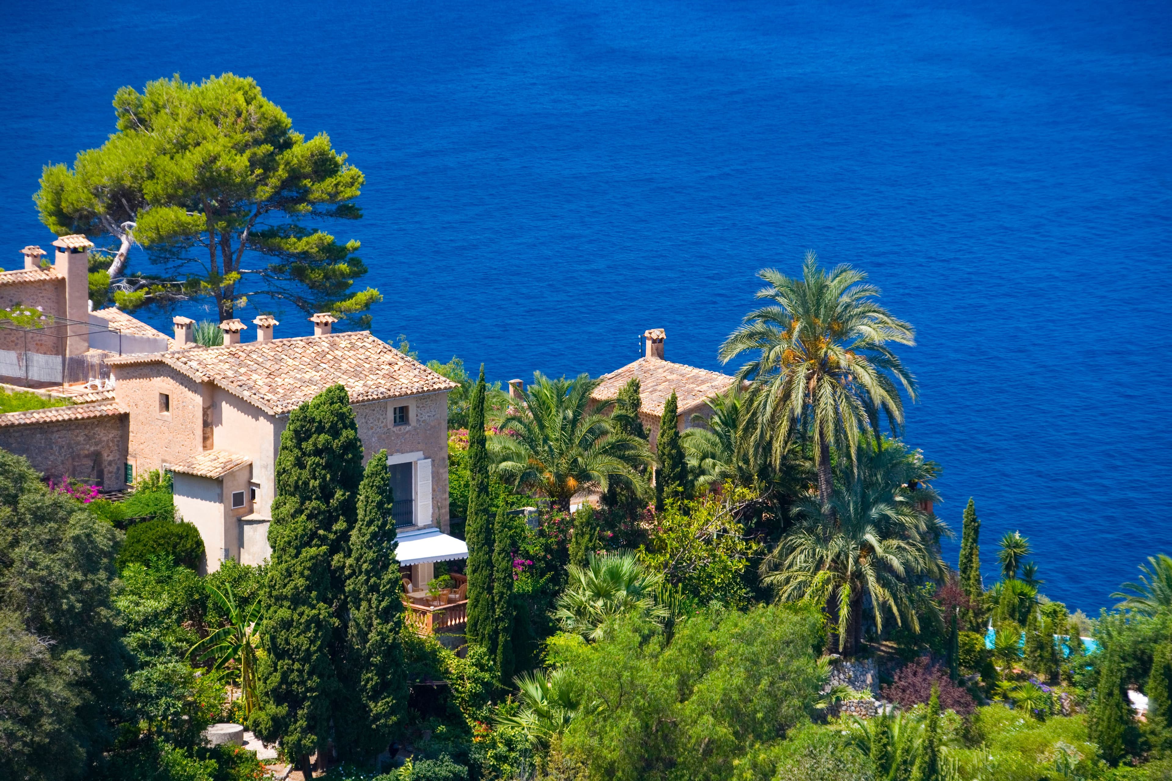 View of sea and rooftops Llucalcari village, Majorca, Spain