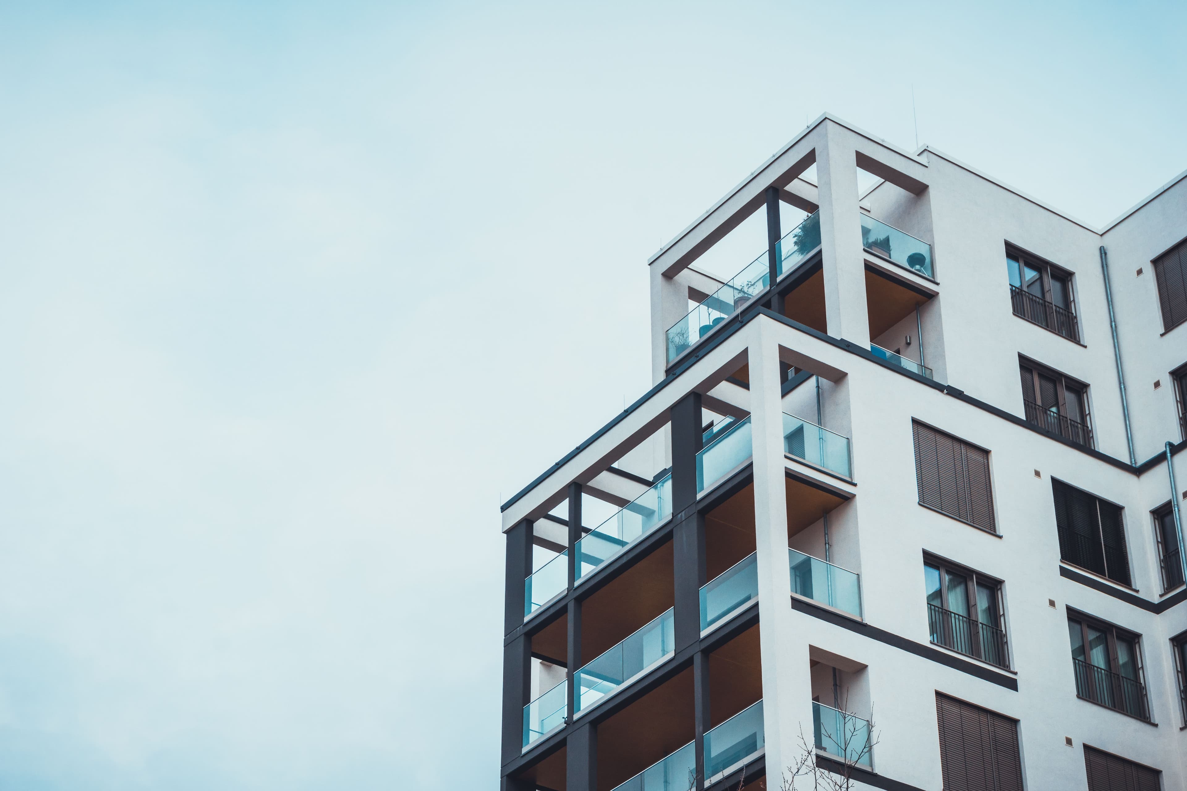 Low Angle View On White And Brown Condominium Building With Open Roof Balconies Under Overcast Sky